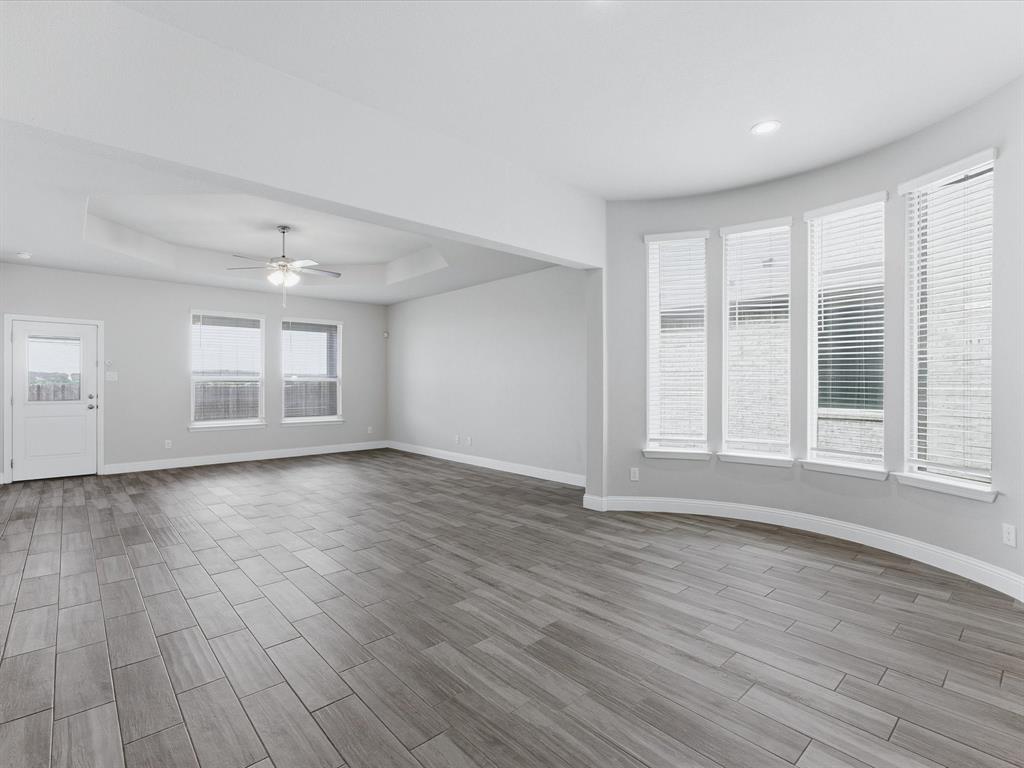 1121 Knightsbridge Road Argyle, TX 76226 - Photo 18 of 39 Expansive living area featuring wood-finish tile flooring and a tray ceiling with a flush-mount ceiling fan