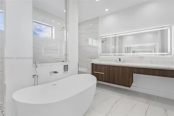 a bathroom with a tub a sink and mirror