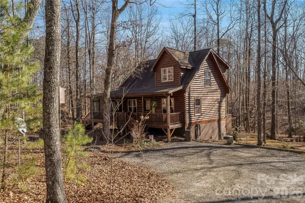 a view of a wooden house with a yard and large trees