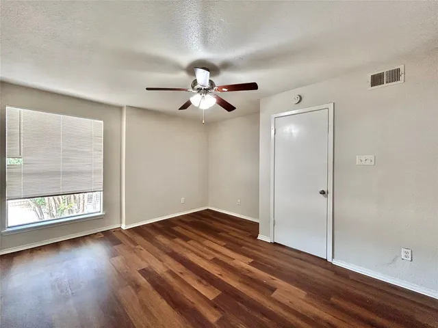 a view of an empty room with a window and wooden floor
