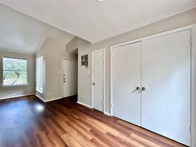 a view of an empty room with wooden floor and closet