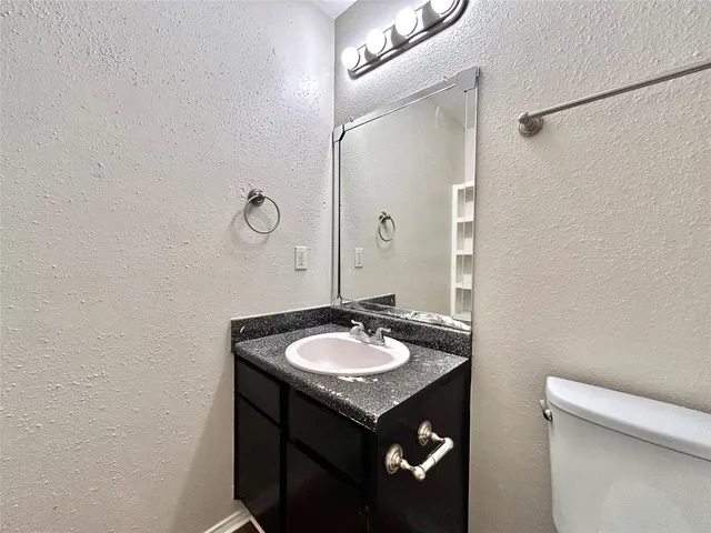 a bathroom with a granite countertop sink a toilet and a mirror