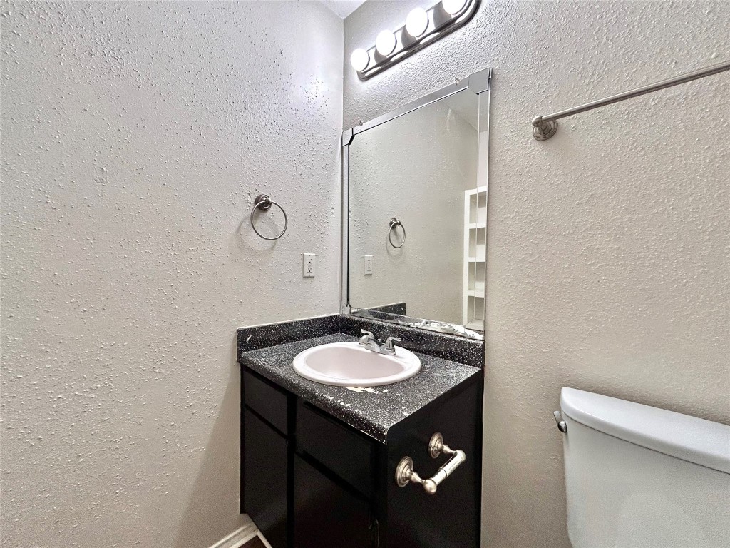 7111 East Highway 290, Unit C Austin, TX 78723 - Photo 16 of 20 a bathroom with a granite countertop sink a toilet and a mirror