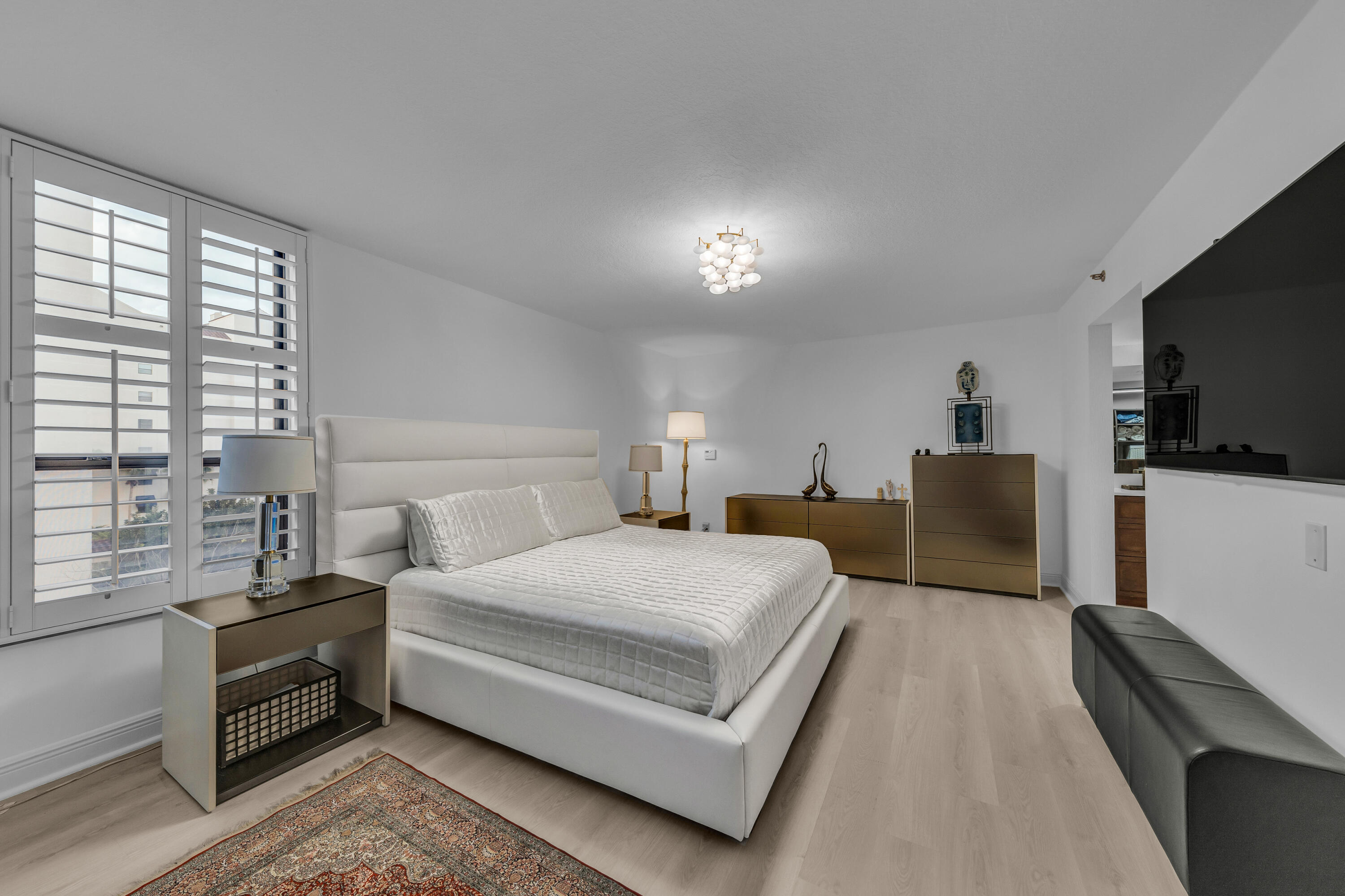 7572 Regency Lake Drive, Unit 402 Boca Raton, FL 33433 - Photo 19 of 31 a spacious bedroom with a bed and a flat screen tv