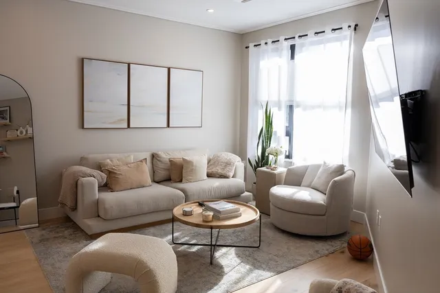 a living room with furniture a flat screen tv and a window