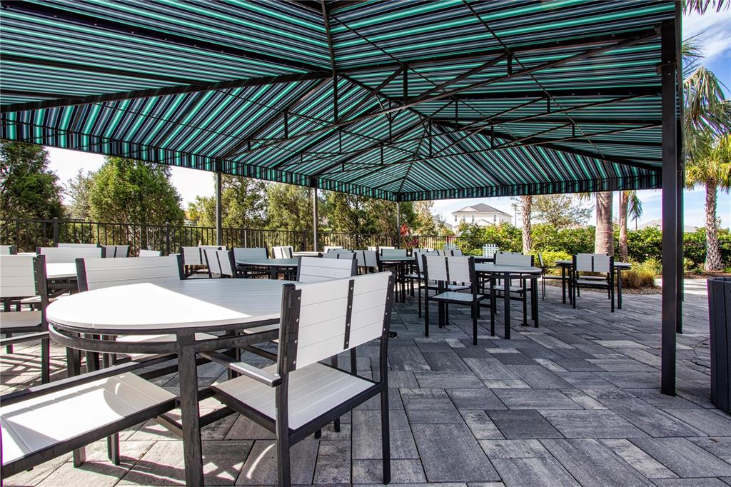 4304 Fly Rod Terrace Parrish, FL 34219 - Photo 87 of 97 a view of a patio with table and chairs under an umbrella with a barbeque