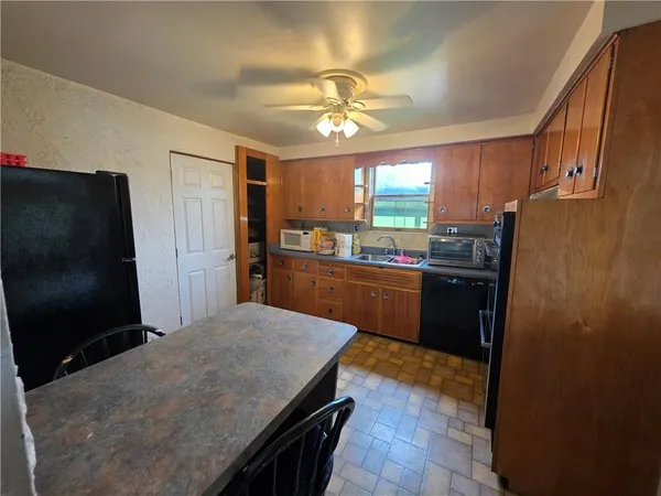 a kitchen with stainless steel appliances granite countertop a refrigerator a sink a stove a microwave a dining table and chairs with wooden floor