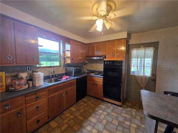 a kitchen with stainless steel appliances granite countertop a refrigerator a sink dishwasher a stove a dining table and chairs with wooden floor