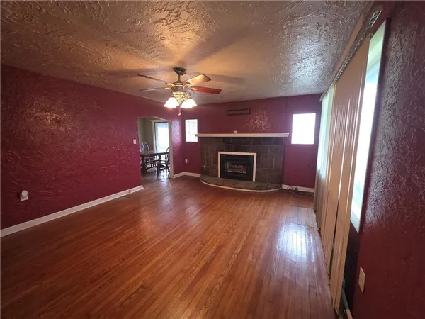 an empty room with wooden floor fireplace and a window