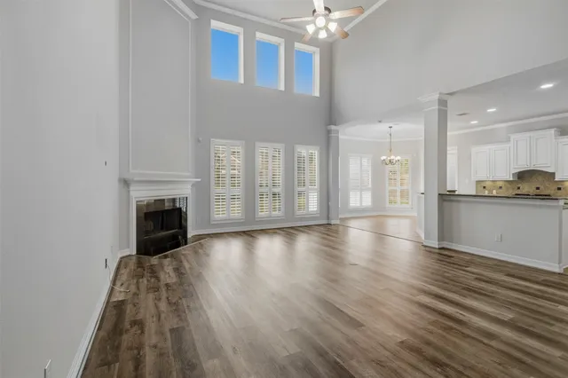 a view of an empty room with wooden floor and a kitchen