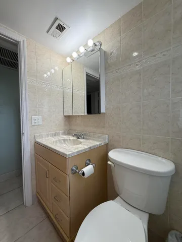 a bathroom with a granite countertop toilet sink and mirror