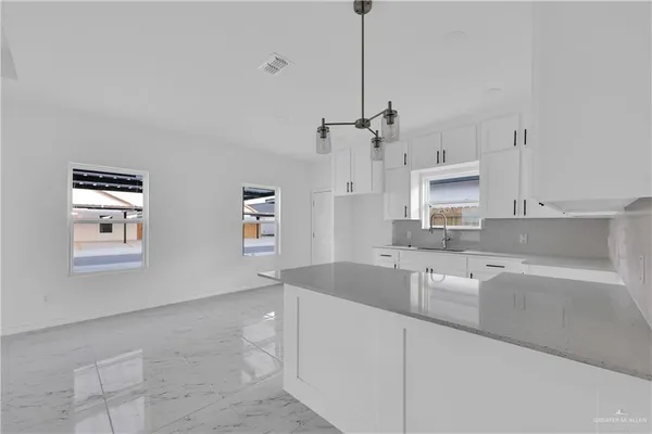 a kitchen with granite countertop a sink a counter space appliances and cabinets