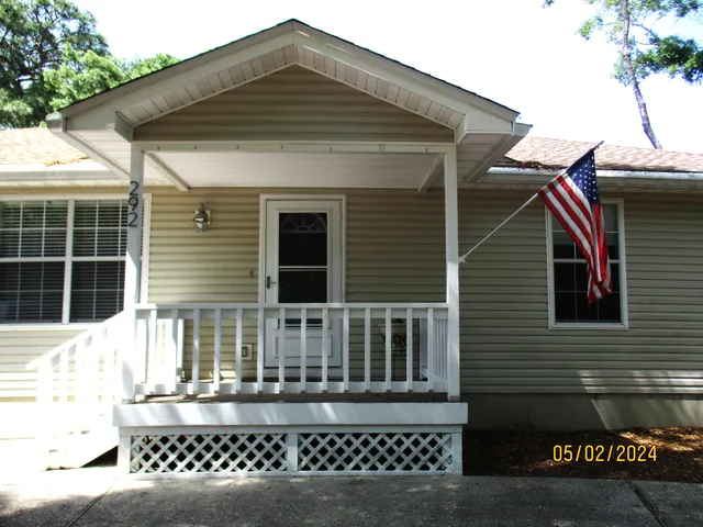 a backyard of a house with table and chairs under an umbrella