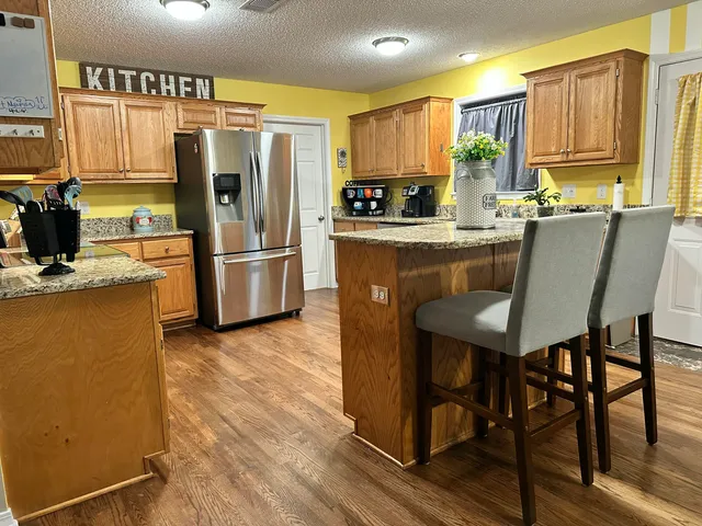 a kitchen with a refrigerator a stove a sink and a dining table with wooden floor