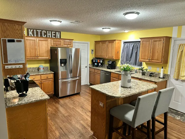 a kitchen with stainless steel appliances granite countertop a sink refrigerator and microwave