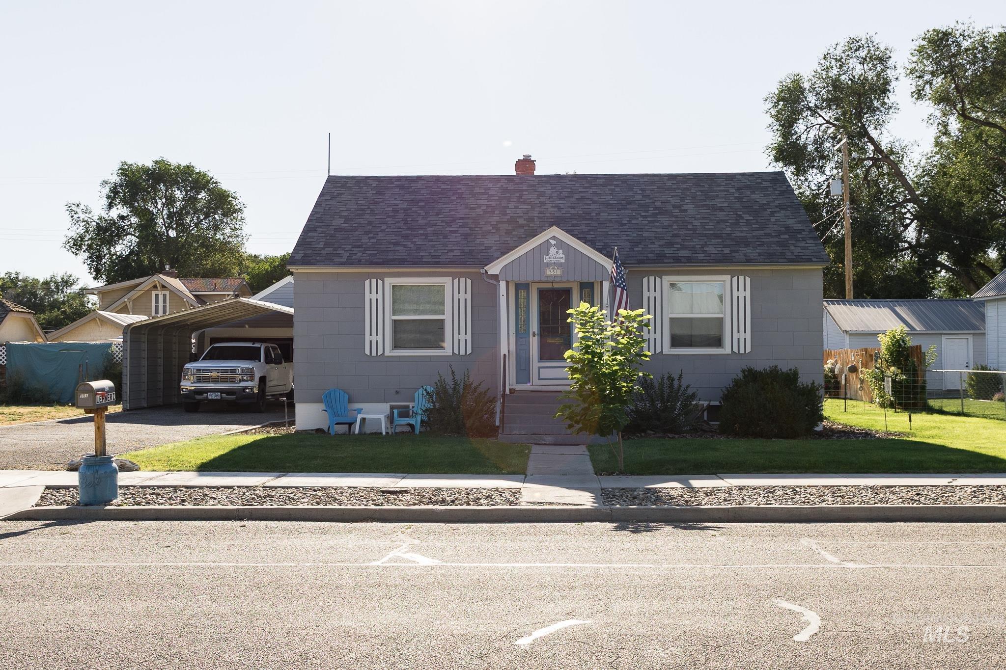 Bungalow-style home with driveway, a shingled roof, a chimney, and a detached carport