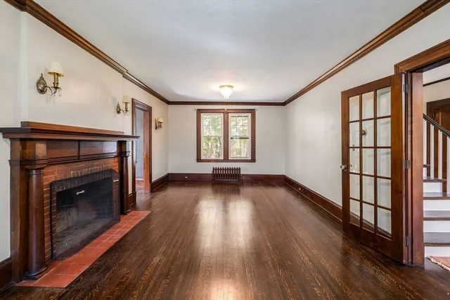 an empty room with wooden floor fireplace and windows