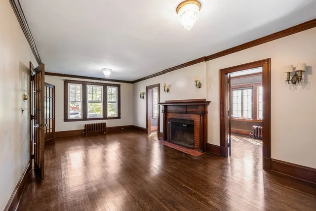 an empty room with wooden floor fireplace and windows