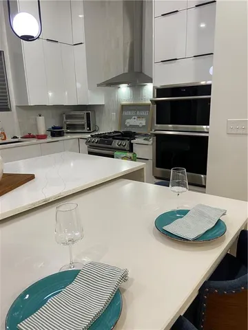 a kitchen with stainless steel appliances a sink a stove a microwave a sink a refrigerator white cabinets and wooden floor