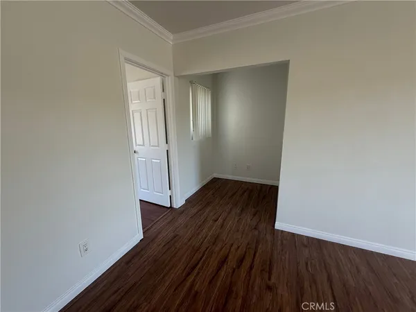 a view of an empty room with wooden floor and closet