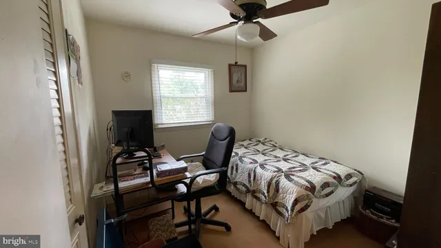 a bedroom with a bed table chair and a window