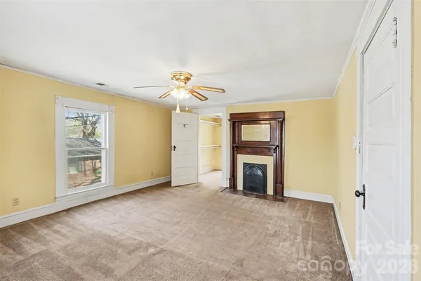 an empty room with windows and fireplace