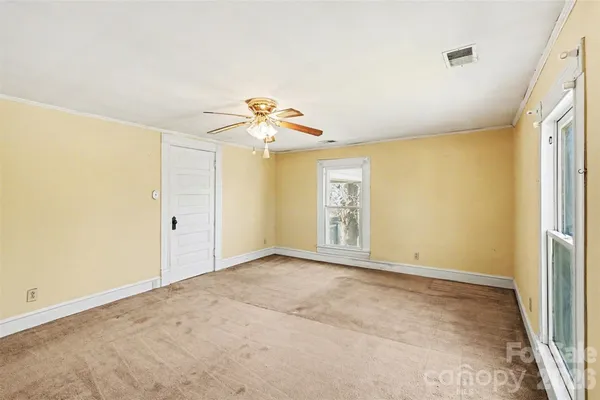 an empty room with windows and chandelier fan