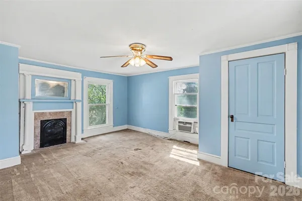 an empty room with windows and fireplace