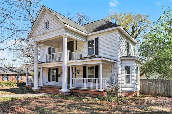 a view of a white house with large windows and a small yard
