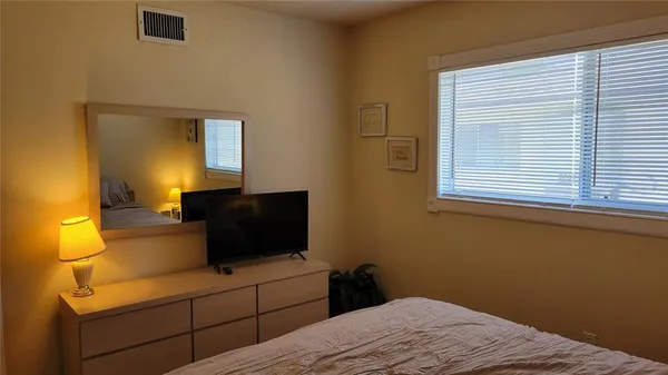 a bedroom with a bed and a flat tv screen on dresser