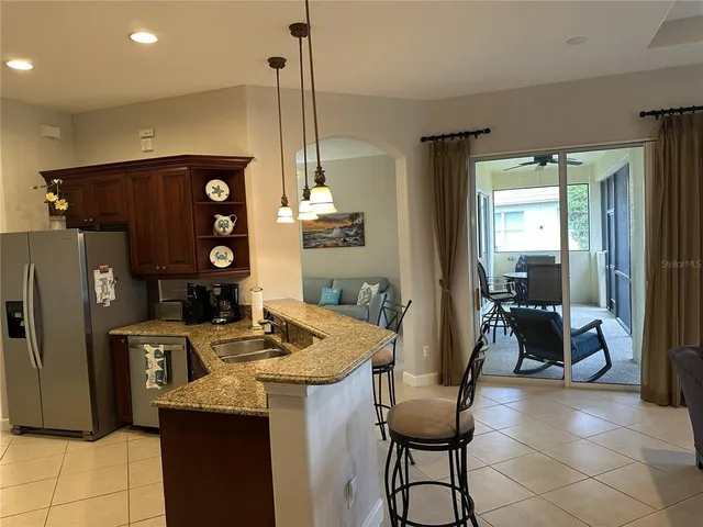 a kitchen with stainless steel appliances kitchen island granite countertop a refrigerator a stove and white cabinets