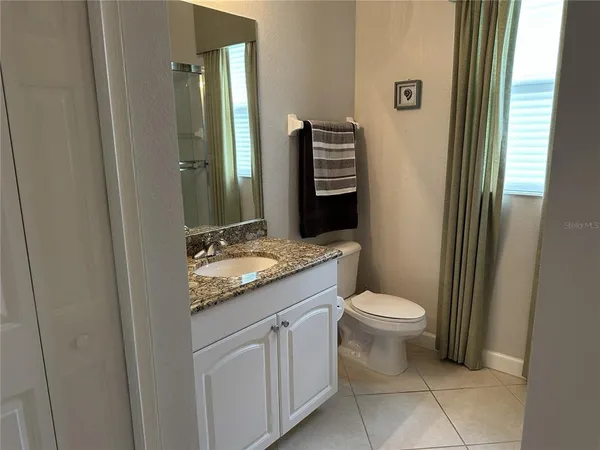 a bathroom with a granite countertop sink toilet and mirror