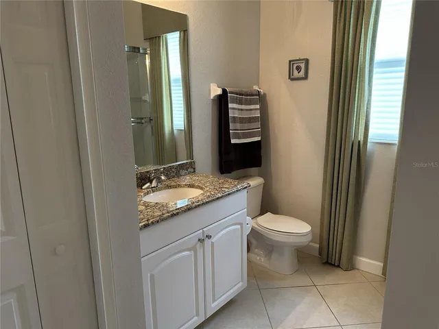 a bathroom with a granite countertop sink toilet and mirror