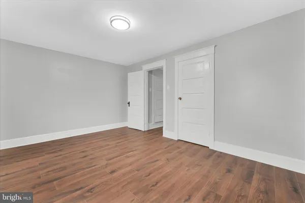 an empty room with wooden floor closet and windows