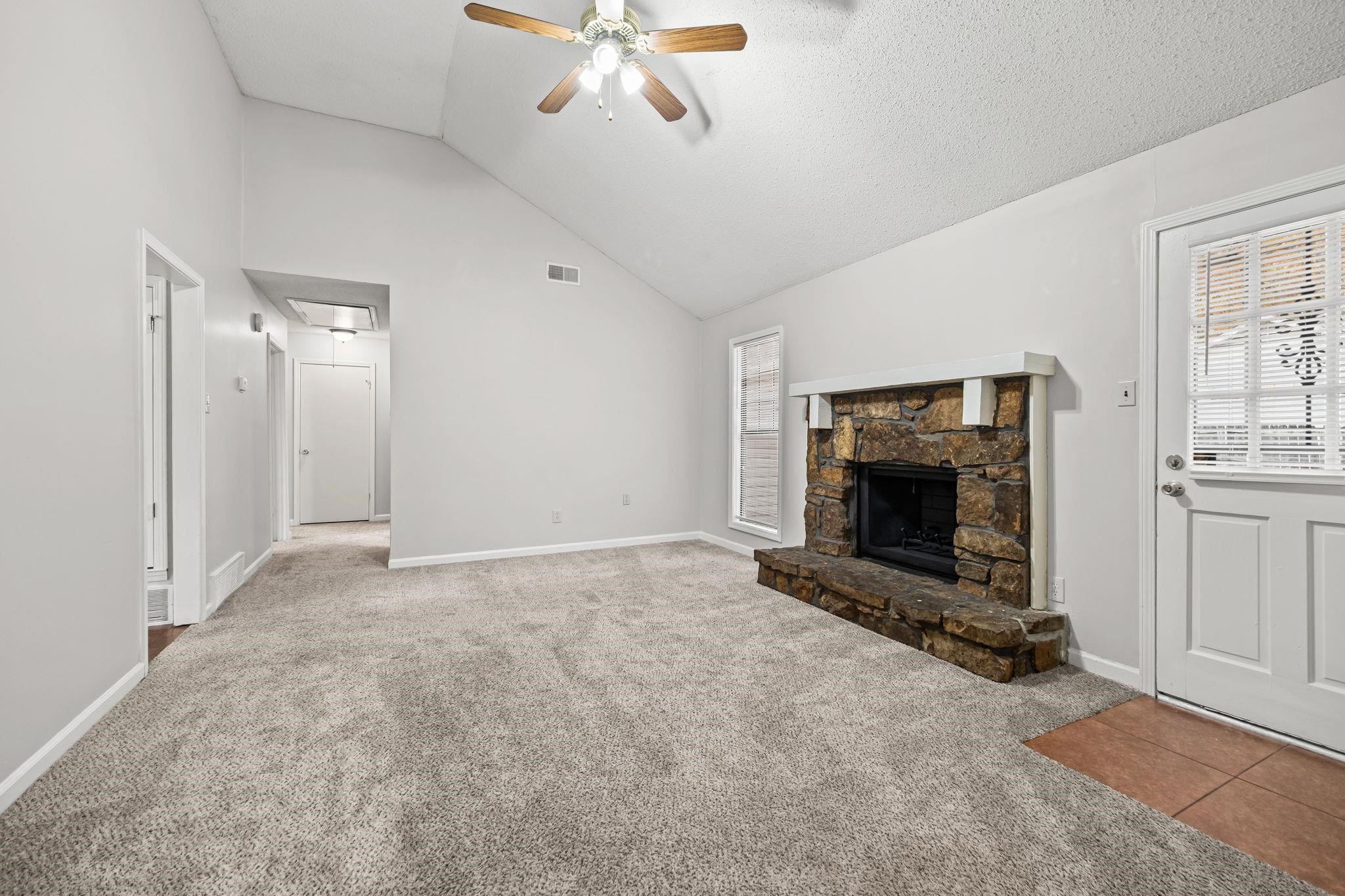 6730 Birch Run Lane Memphis, TN 38115 - Photo 6 of 20 Unfurnished living room featuring carpet, high vaulted ceiling, attic access, a ceiling fan, and a fireplace