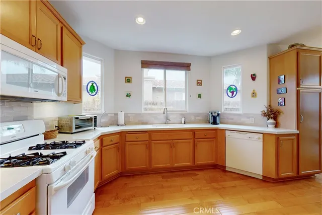 a kitchen with stainless steel appliances granite countertop a sink a stove a refrigerator cabinets and a window