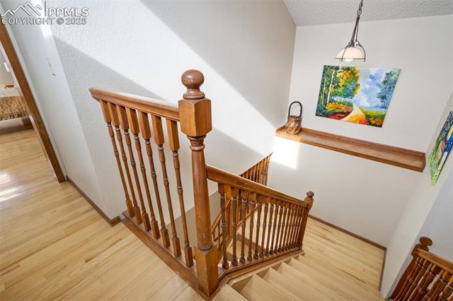 4385 Sandstone Road Monument, CO 80132 - Photo 32 of 50 Stairway with wood finished floors and a textured ceiling