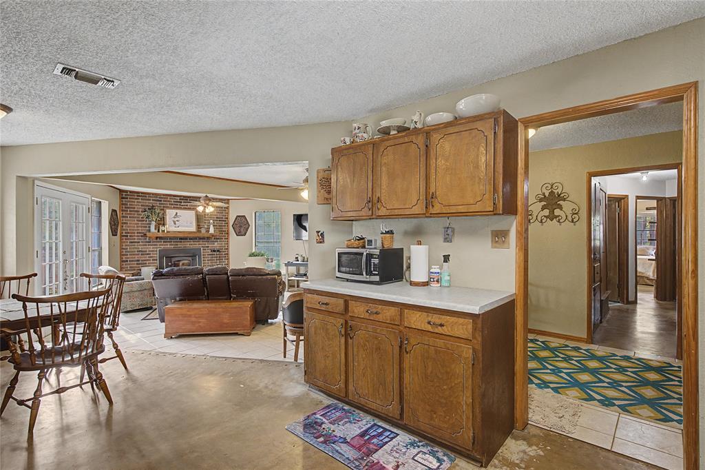 243 County Road 3851 Poolville, TX 76487 - Photo 14 of 34 a open kitchen with stainless steel appliances granite countertop a stove top oven a dining table and chairs with wooden floor