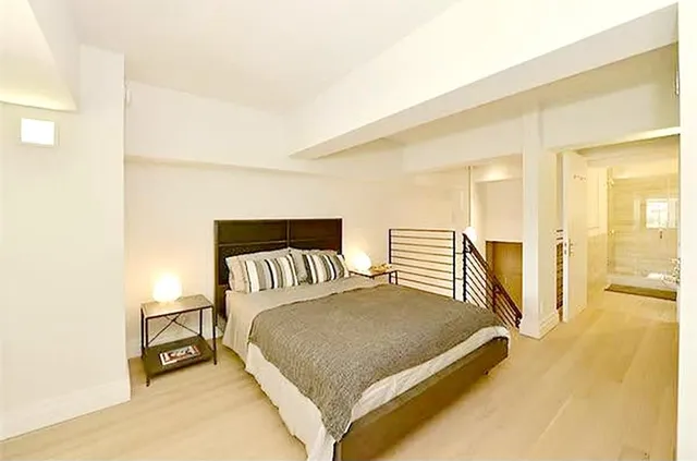 a spacious bedroom with a bed and wooden floor