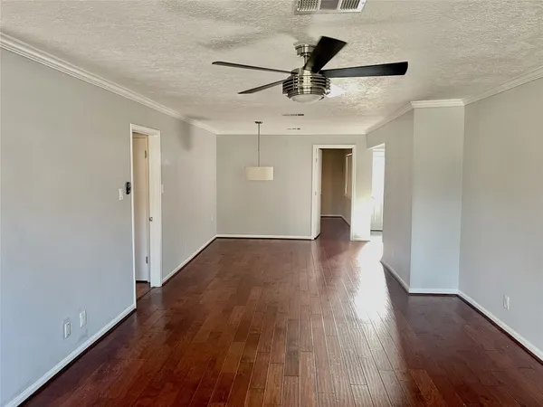 a view of a big room with wooden floor a ceiling fan and entryway