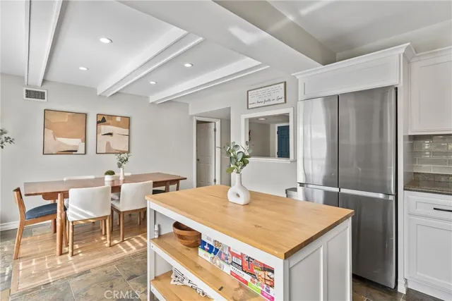 a view of kitchen with stainless steel appliances granite countertop table chairs and a refrigerator