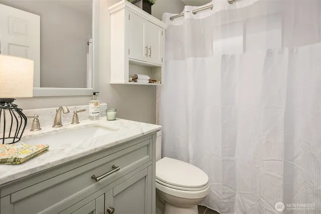 a bathroom with a granite countertop sink and a toilet