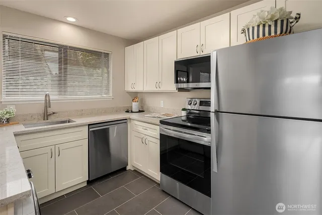 a kitchen with stainless steel appliances a refrigerator sink and microwave