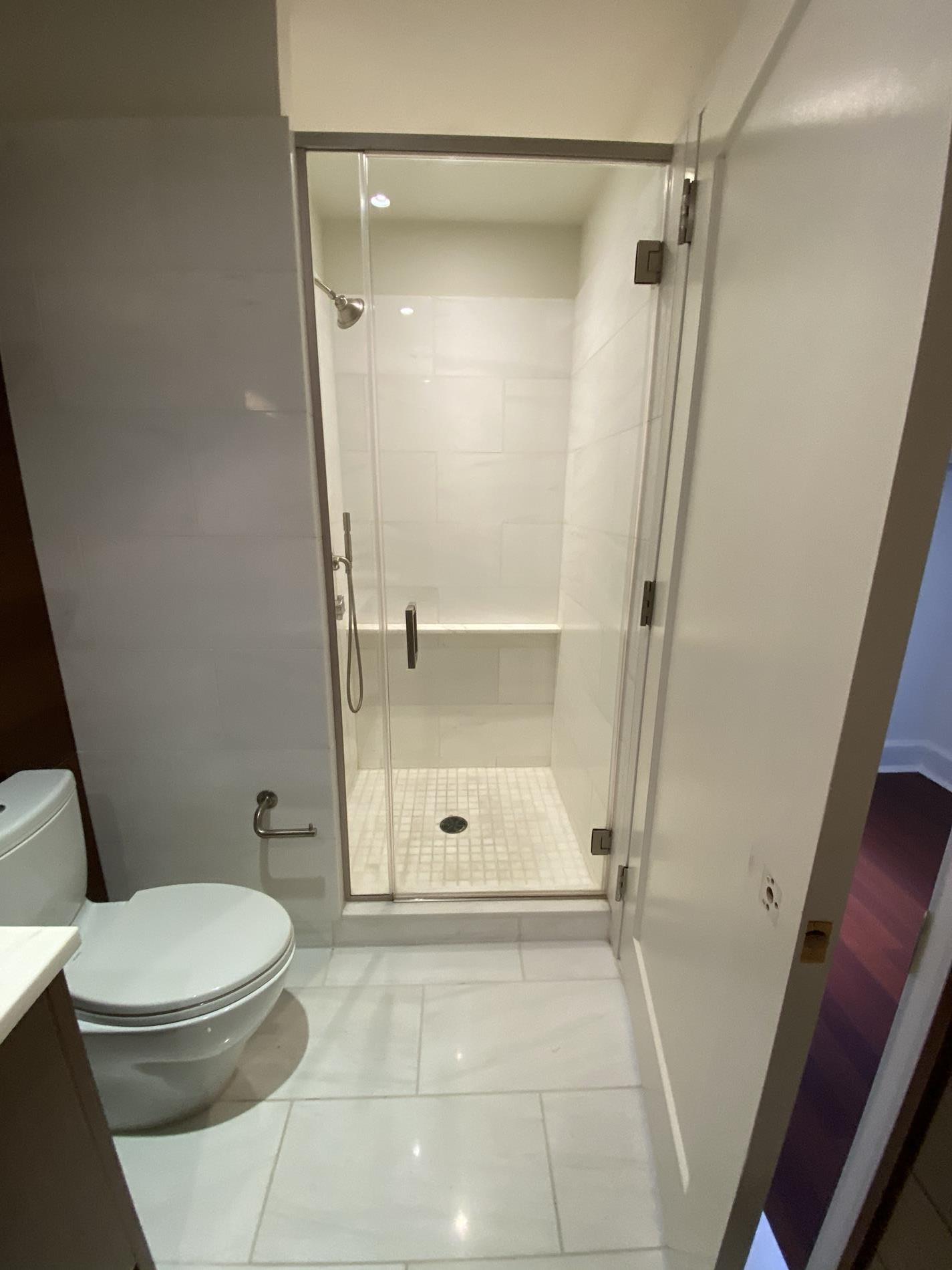 a bathroom with a glass door shower and toilet