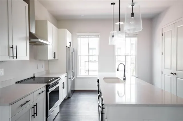 a kitchen with stainless steel appliances granite countertop a sink stove and white cabinets with wooden floor