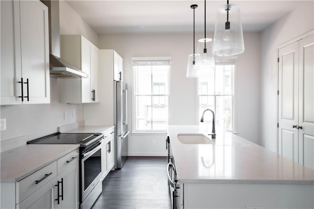 709 Needletail Way Atlanta, GA 30312 - Photo 11 of 29 a kitchen with stainless steel appliances granite countertop a sink stove and white cabinets with wooden floor
