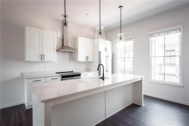 a kitchen with stainless steel appliances granite countertop a sink a window and white cabinets