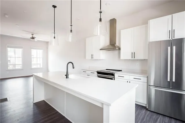 a kitchen with stainless steel appliances a refrigerator a sink and wooden floors