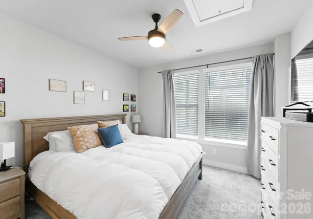 a bedroom with a large bed and a chandelier next to a window