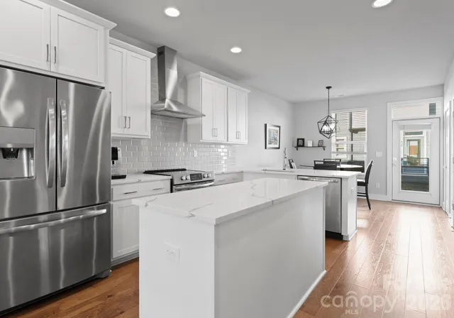 a kitchen with stainless steel appliances white cabinets and wooden floor